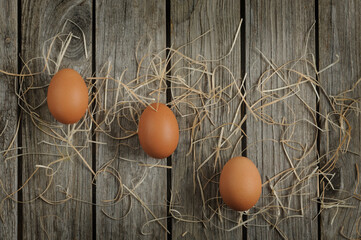 Three brown chicken eggs on a wooden board. Flat lay, top view with copy space