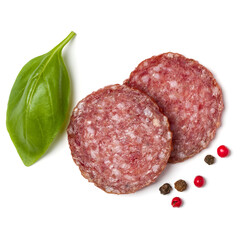 Slices of salami isolated on white background closeup. Sausage and basil leaves top view.