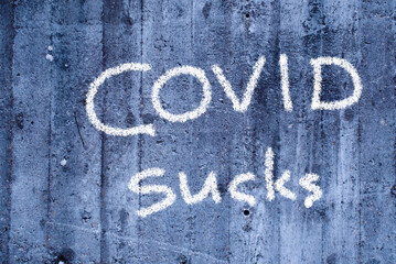 writing on concrete wall: covid sucks