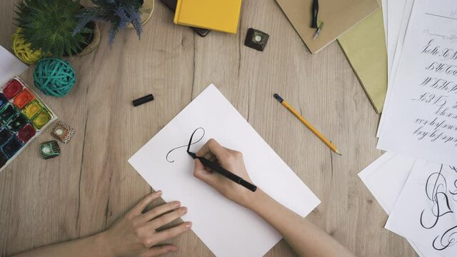 Female Hand is Writing Calligraphic Twirl view from above