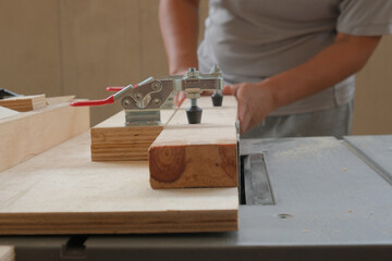 Selective focus picture of jig holding wood while trimming on saw table.