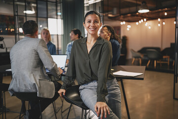 Smiling businesswoman sitting with colleagues at an office table