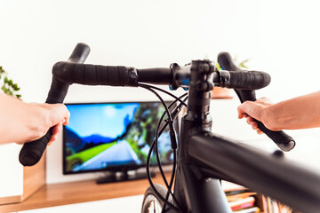 Cycling Indoor with exercise bike trainer motivating himself with the gamification of sport.