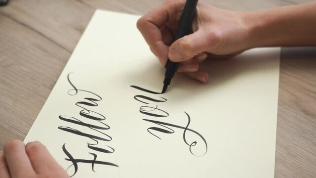 Female Hand is Writing Follow your dreams in Calligraphic Form / Close Up