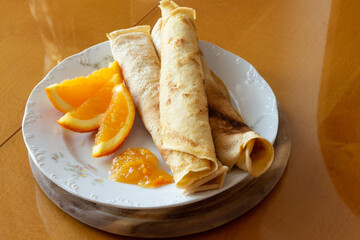 Crepes with orange jam and oranges  - wooden background