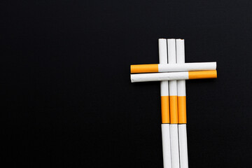 The cross is made of cigarette on dark background. Non smoking for health concept