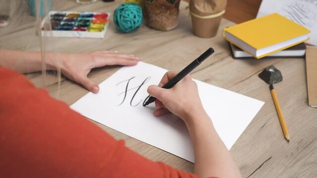 Woman is Writing Hello with Brush Pen in Calligraphy Way 