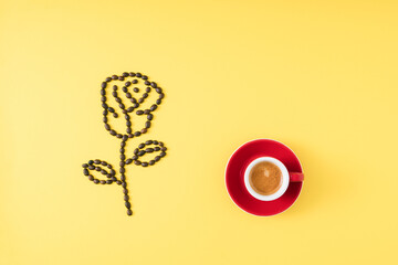 Rose made of coffee beans on trendy yellow background with espresso coffee. Minimal woman's day concept. Creative background design.