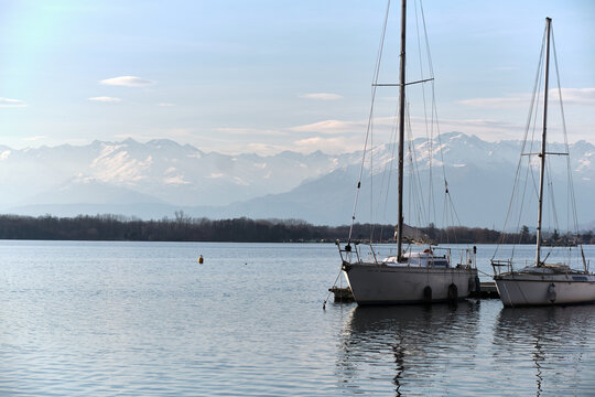 two sailboats moored on the pier of an alpine lake with the mountains in the background