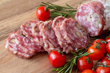 Sliced Air-dried salami with rosemary and cherry tomatoes - wood background