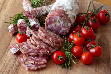 Sliced Air-dried salami with rosemary and cherry tomatoes - wood background