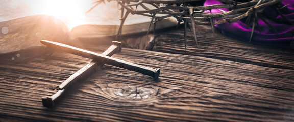 Three Crucifixion Spikes In Shape Of Cross On Wooden Table With Bible, Crown Of Thorns And Purple...