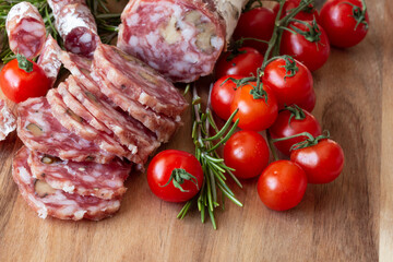 Sliced Air-dried salami with rosemary and cherry tomatoes - wood background
