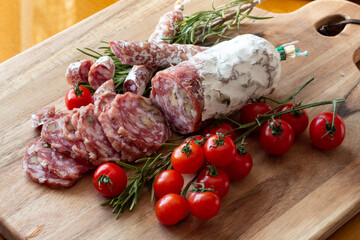 Sliced Air-dried salami with rosemary and cherry tomatoes - wood background