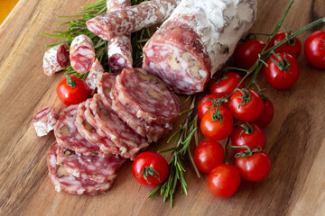 Sliced Air-dried salami with rosemary and cherry tomatoes - wood background
