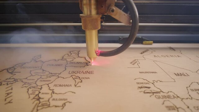 Cnc laser cutting machine cuts world map on wooden plank and plywood