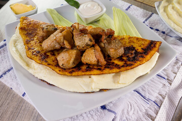 Comida típica de Venezuela servido en plato para restaurante, cachapas con relleno de queso jamón, cochino frito