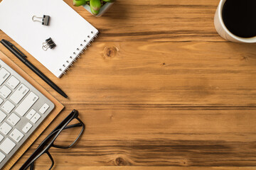 Overhead above close up view photo of note book paper clip pen keyboard eyewear cup of espresso isolated wooden brown backdrop