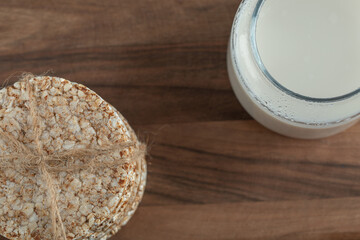 Glass of milk with crispbread on wooden board