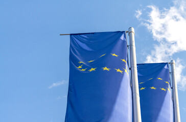 Flags of the European Union EU on poles against blue sky
