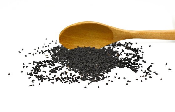 Heap of black nigella seeds in a wooden spoon. Pile of black cumin seeds spice isolated on white background.