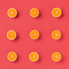 Fruit pattern of fresh orange tangerine or mandarin over living coral background. Flat lay, top view. Pop art design, creative summer concept. Citrus in minimal style..