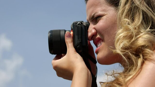 Female photographer takes pictures on summer day - side profile