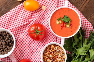 Delicious tomato cream soup on a wooden background. Top view. With vegetables, bell peppers, herbs and tomatoes.