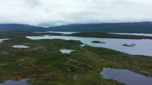 Aerial view of rocky, arctic nature and fells at lake Tornetrask, gloomy, summer day, in Sweden	- tracking, drone shot
