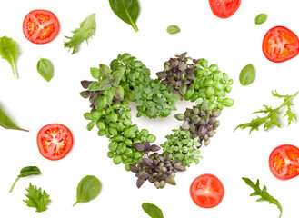 Creative layout made of tomato slices and lettuce salad leaves. Varieties of basil arrangement in form of heart. Flat lay, top view. Food concept. Vegetables isolated on white background.
