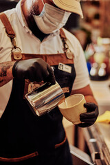 Hombre joven latino con tatuaje y tapaboca  sirviendo un cafe