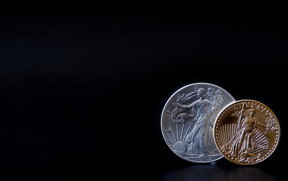 A gold and silver coin in corner of a black backdrop