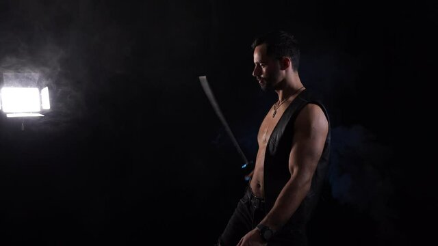 Muscular Man playing with long sword isolated on black background