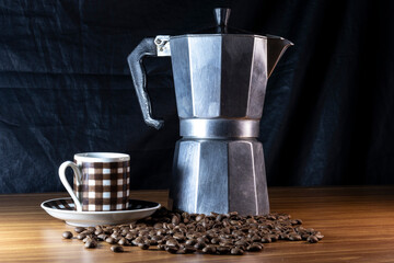 Coffee beans in a cup and Italian coffee maker on a wooden table in Brazil