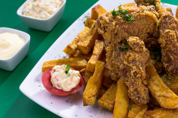 Plato de comida hecho de chicharrón de pollo, frito, broaster con papas fritas en plato blanco para restaurante en fondo verde