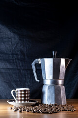 Coffee beans in a cup and Italian coffee maker on a wooden table in Brazil