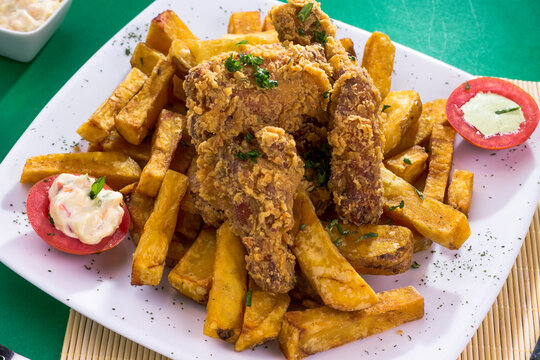 Plato de comida hecho de chicharr&oacute;n de pollo, frito, broaster con papas en plato blanco con papas fritas