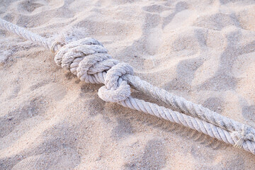 Knotted rope on sand beach. conceptual stability concept.