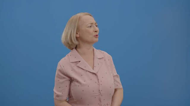 Surprised, panicked, the obviously sad old woman looks around.Shocked woman. Studio shot isolated on blue background.