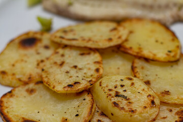 potato with fish, roasted chopped potatoes, roasted potatoes, potetoes slices roasted, meal with fish in the background