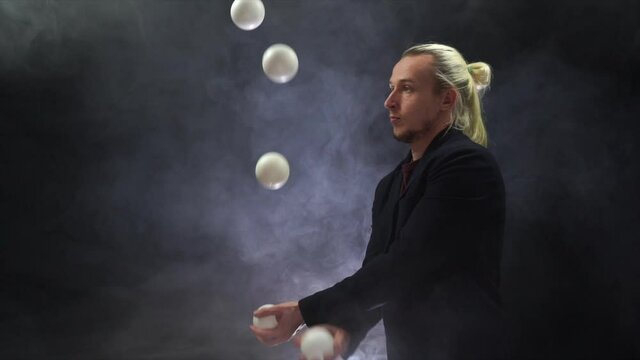 Man wearing a black juggling with white balls. Management, control and success