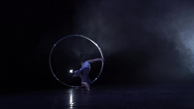 Circus artist shows concentration and balance while spinning on a Cyr wheel