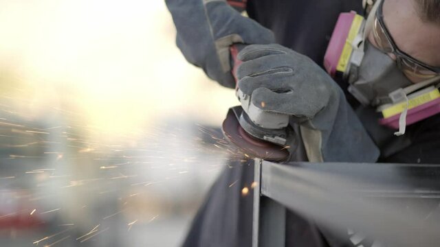 Metal worker polishing metal construction corner with angle grinder