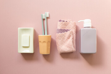 Spa bathroom products. Soap bar, toothbrush, towel, shampoo bottle on pink background. top view