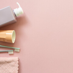 Spa bathroom products. Shampoo bottle, cup, toothbrush, towel on pink background. top view, copy space