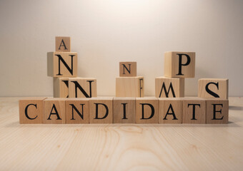 The word candidate is from wooden cubes. Background from wooden letters.