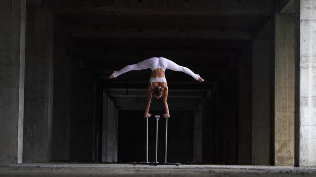 Flexible female circus Artist keeps balance on hands in the abandoned building. Handstand and equilibrium concept 