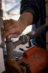 Mano masculina reparando bomba de agua y tuberías en época de sequía