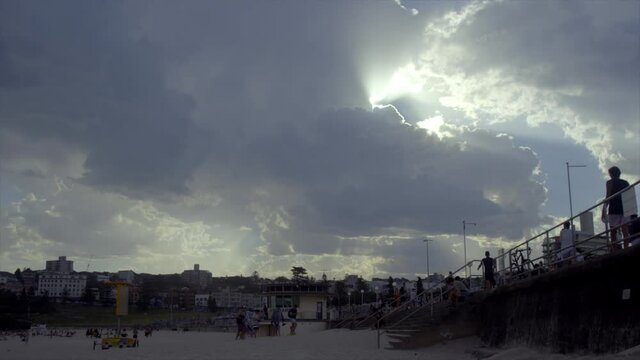 Time Lapse: White clouds with sun rays behind moving across the sky over Bondi Beach, Australia