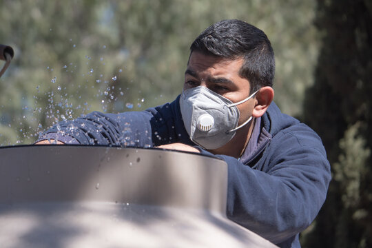 Hombre mexicano de mediana edad revisa su suministro de agua despu&eacute;s de desabasto durante la pandemia COVID-19 porta mascarilla KN95